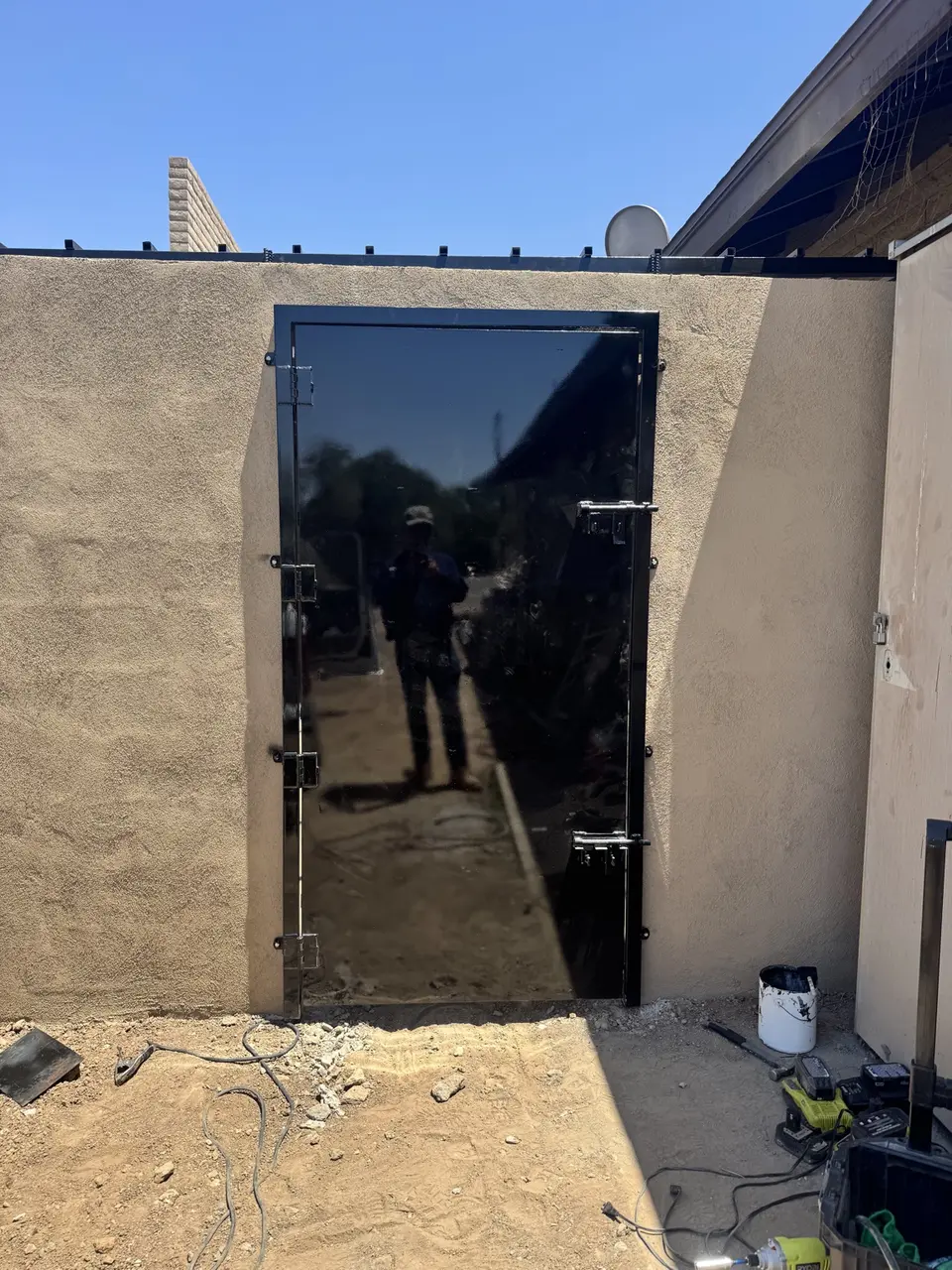 Close view of black steel access gate installed in stucco CMU enclosure